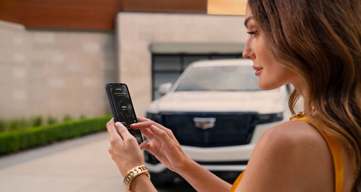 lady checking her mobile with a Cadillac vehicle background | King O'Rourke Cadillac in Smithtown NY