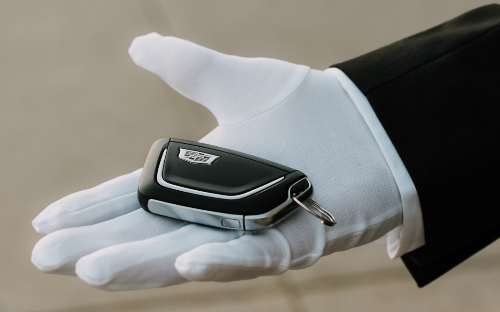 Image of a Cadillac vehicle key placed in a white gloved hand